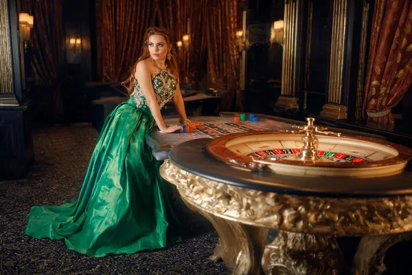 A woman in a luxurious green gown next to an ornate roulette wheel, capturing the upscale casino mood of KKFB.